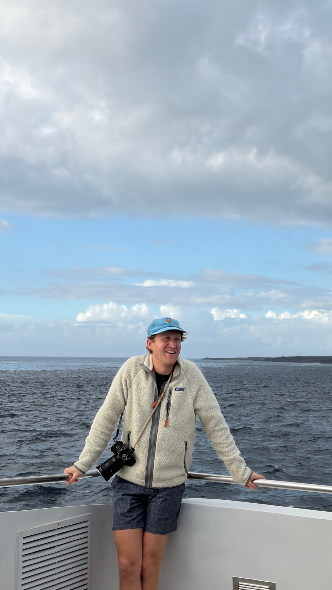 Nick Tearle on a boat with a camera, offshore under a cloudy sky